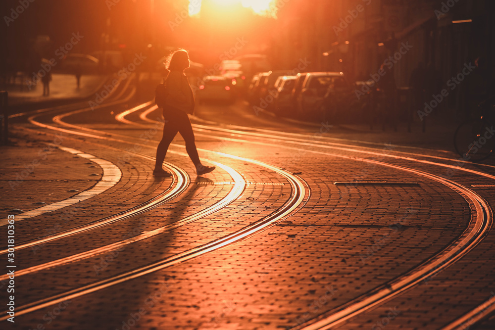 Φωτογραφία Street photography, selective focus on Tram rail with  blurred woman walking on tram railway during the sunset in Bordeaux city, France