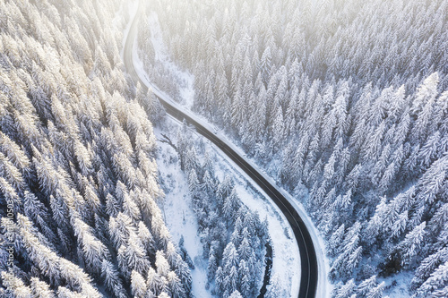 Aerial view on the road and forest at the winter time. Natural winter landscape from air. Forest under snow at the winter time. Winter travel - image © biletskiyevgeniy.com