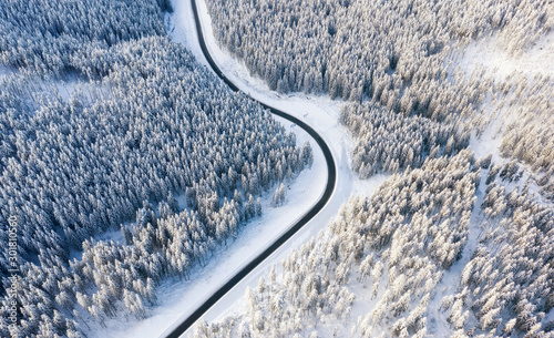 Aerial view on the road and forest at the winter time. Natural winter landscape from air. Forest under snow at the winter time. Winter travel - image