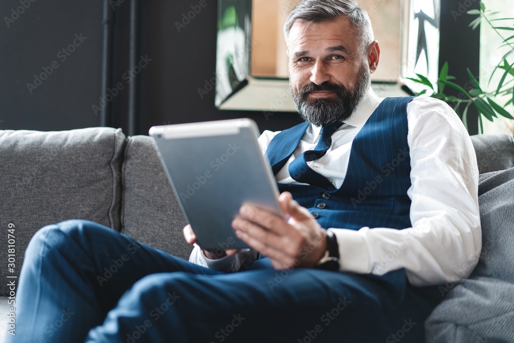 smiling businessman with digital tablet sitting on sofa
