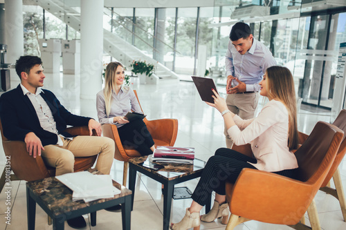 Business team working on new project and smiling. Man and women sitting together in modern office for project discussion.
