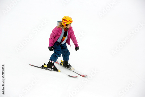 Young active girl skies downhill without sticks in yellow helmet and pink coat. Cut out, separated by snow and fogy weater.