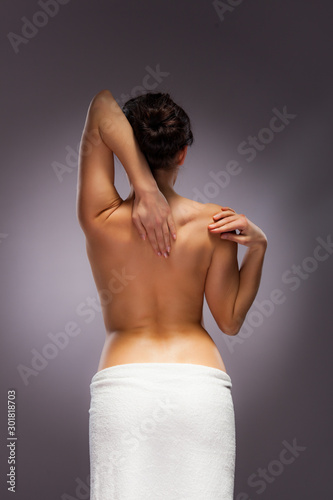 Woman massaging back pain on grey background