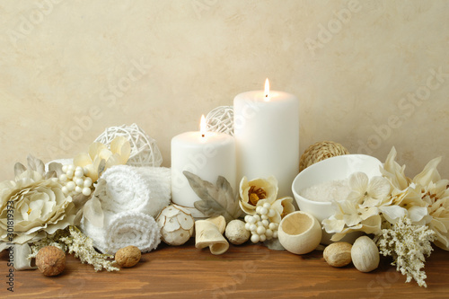 spa concept of white burning candles arranged with natural potpourri elements and flowers with bath slats on a warm background