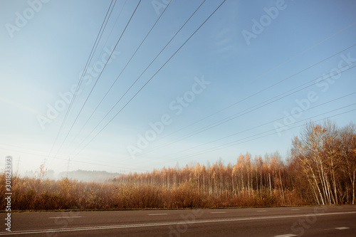 Electric transmission lines with electricity in the foggy morning autumn forest.