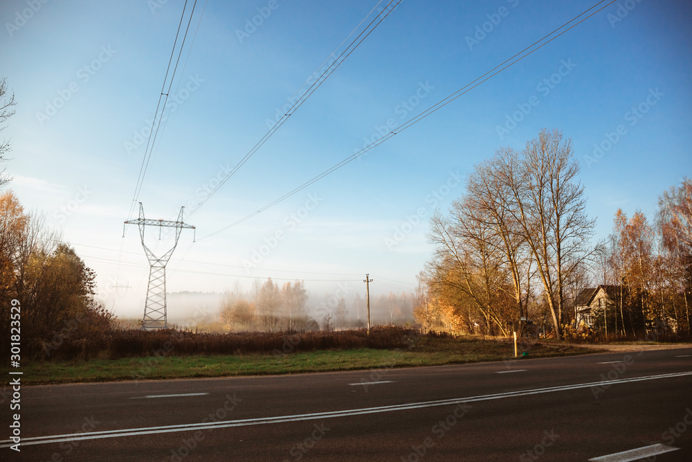 Electric transmission lines with electricity on a field in the autumn morning fog Electric transmission lines with electricity on a field in the autumn morning fog