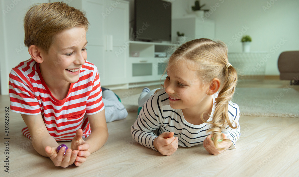 Portrait of two cheerful children laying on the floor and playing with colorful dices Portrait of two cheerful children laying on the floor and playing with colorful dices