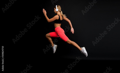 Run hard to get into shape. Woman run black background. Jogger jump with long run. Fit athlete in fashion sportswear. Athletic female sprinter or runner. Active and dynamic. Run fast, finish soon