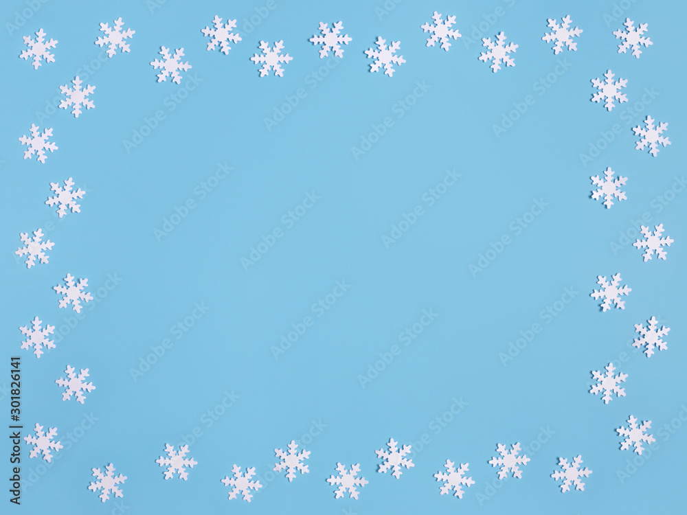 Christmas frame with white snowflakes on pastel blue background. Space for text. Christmas frame with white snowflakes on pastel blue background. Space for text.