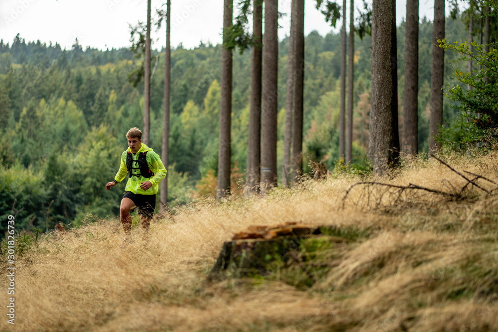 A young athlete in barefoot shoes runs down the mountain. Mountain run. Cross Country Running. Individual sports A young athlete in barefoot shoes runs down the mountain. Mountain run. Cross Country Running. Individual sports