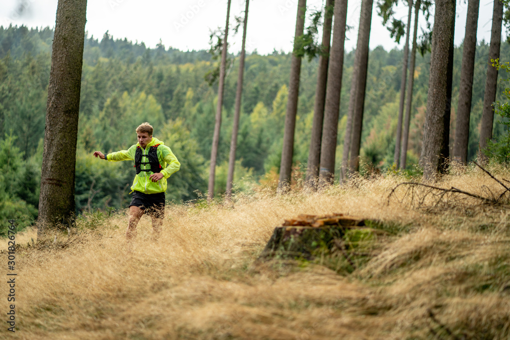 A young athlete in barefoot shoes runs down the mountain. Mountain run. Cross Country Running. Individual sports