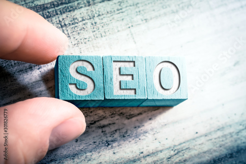 The Word SEO On Wooden Blocks And Arranged By Male Fingers On A Table