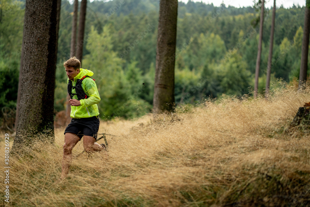 A young athlete in barefoot shoes runs down the mountain. Mountain run. Cross Country Running. Individual sports A young athlete in barefoot shoes runs down the mountain. Mountain run. Cross Country Running. Individual sports