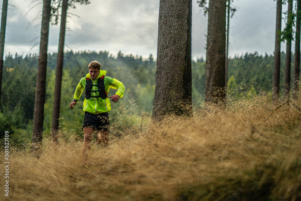 A young athlete in barefoot shoes runs down the mountain. Mountain run. Cross Country Running. Individual sports