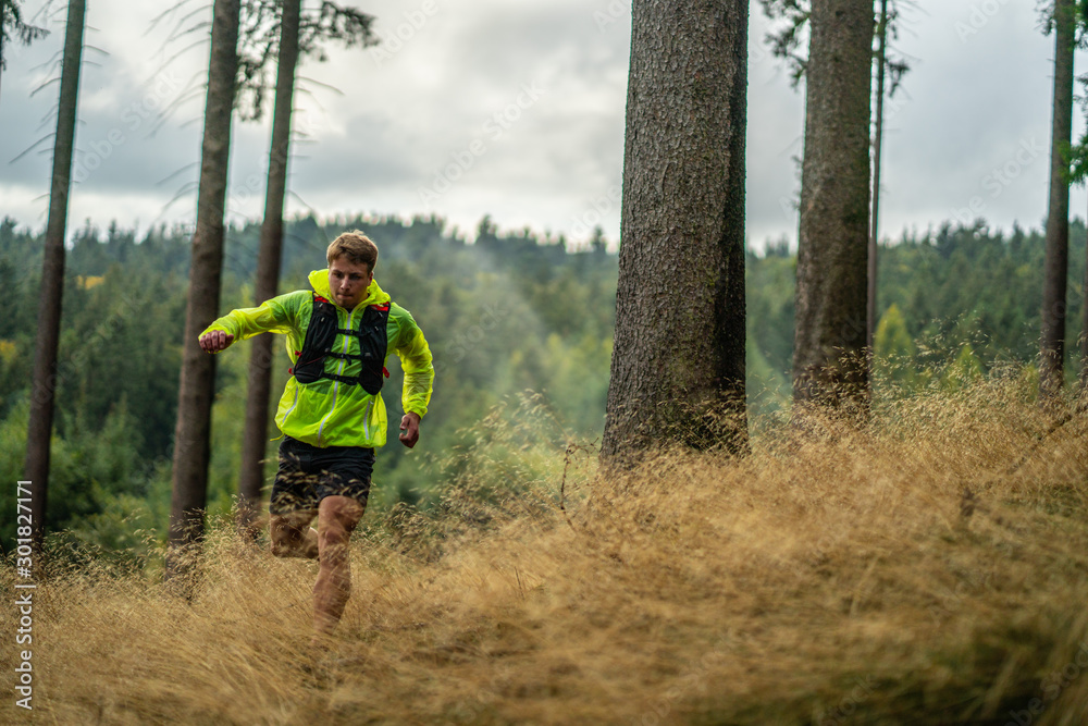 A young athlete in barefoot shoes runs down the mountain. Mountain run. Cross Country Running. Individual sports A young athlete in barefoot shoes runs down the mountain. Mountain run. Cross Country Running. Individual sports