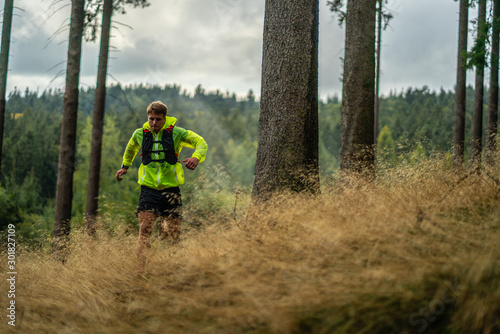 A young athlete in barefoot shoes runs down the mountain. Mountain run. Cross Country Running. Individual sports