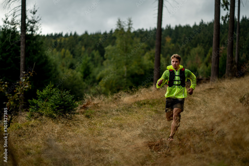 A young athlete in barefoot shoes runs down the mountain. Mountain run. Cross Country Running. Individual sports A young athlete in barefoot shoes runs down the mountain. Mountain run. Cross Country Running. Individual sports