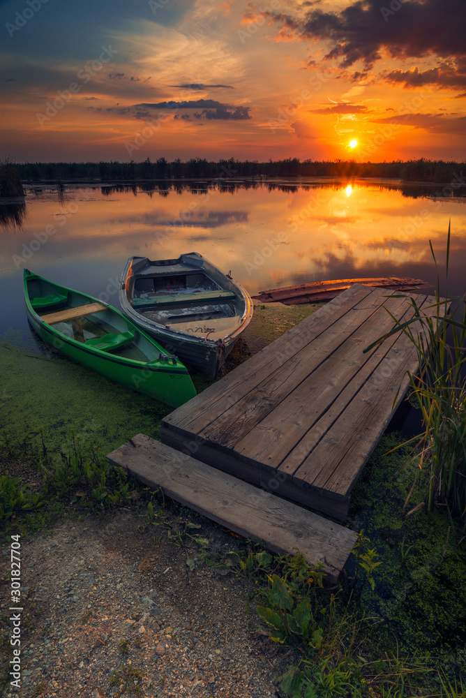 Two boats on a lake near a pontoon at sunrise