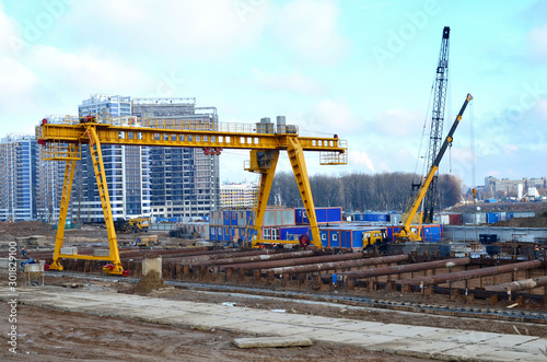 Gantry crane and auto crane working at construction site. Digging a pit for the building of an underground tunnel of the metro line. Subway construction project, Minsk, Belarus, Aerodromnaya street photo