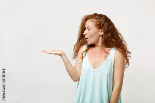 Young amazed shocked redhead woman girl in casual light clothes posing isolated on white background studio portrait. People sincere emotions lifestyle concept. Mock up copy space. Pointing hand aside.