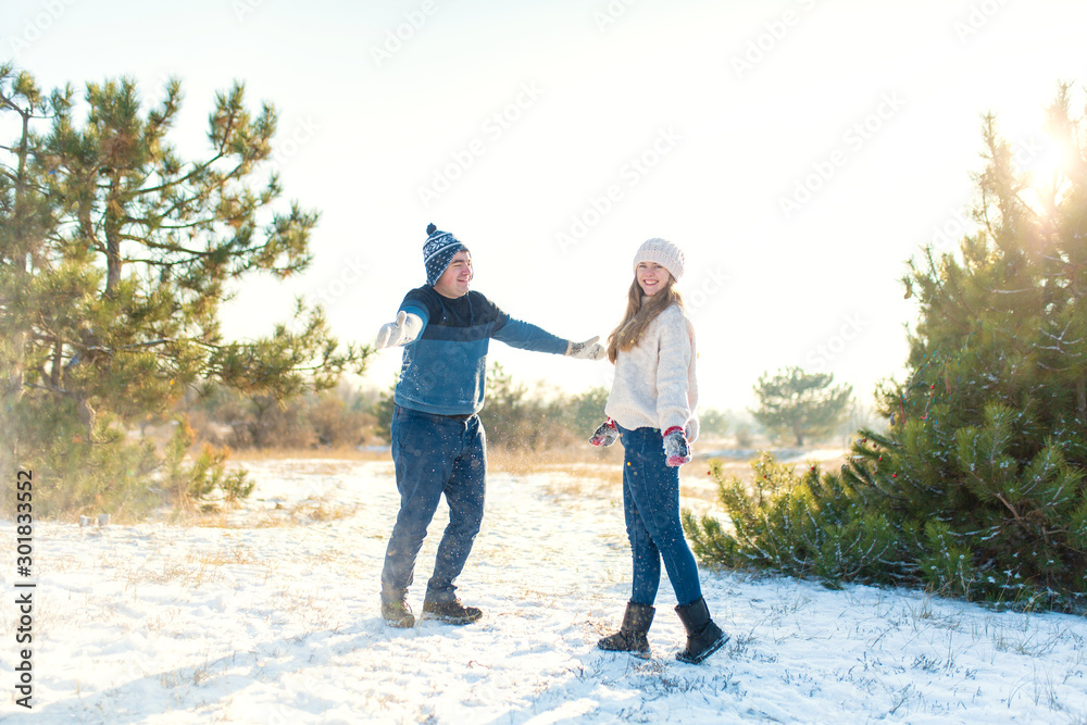 Loving couple play snowballs in winter in the forest. Throw each other snow. Laugh and have a good time