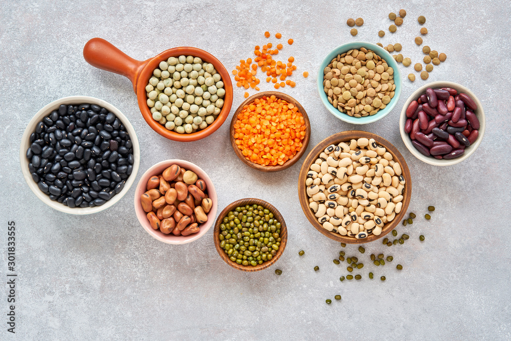 Legumes and beans assortment in different bowls on light stone background . Top view. Healthy vegan protein food. Legumes and beans assortment in different bowls on light stone background . Top view. Healthy vegan protein food.