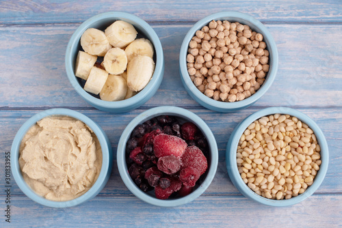 ingredients for making smoothies in bowls - frozen berries, banana, hummus, chickpea and pine nuts