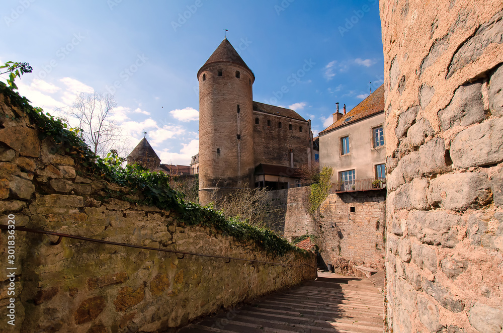 View of the preserved part of the castle in the town of Semur-An-Osois, Burgundy, France. There is a walkway outside the walls with steps and ancient round towers. City landscape. Background.