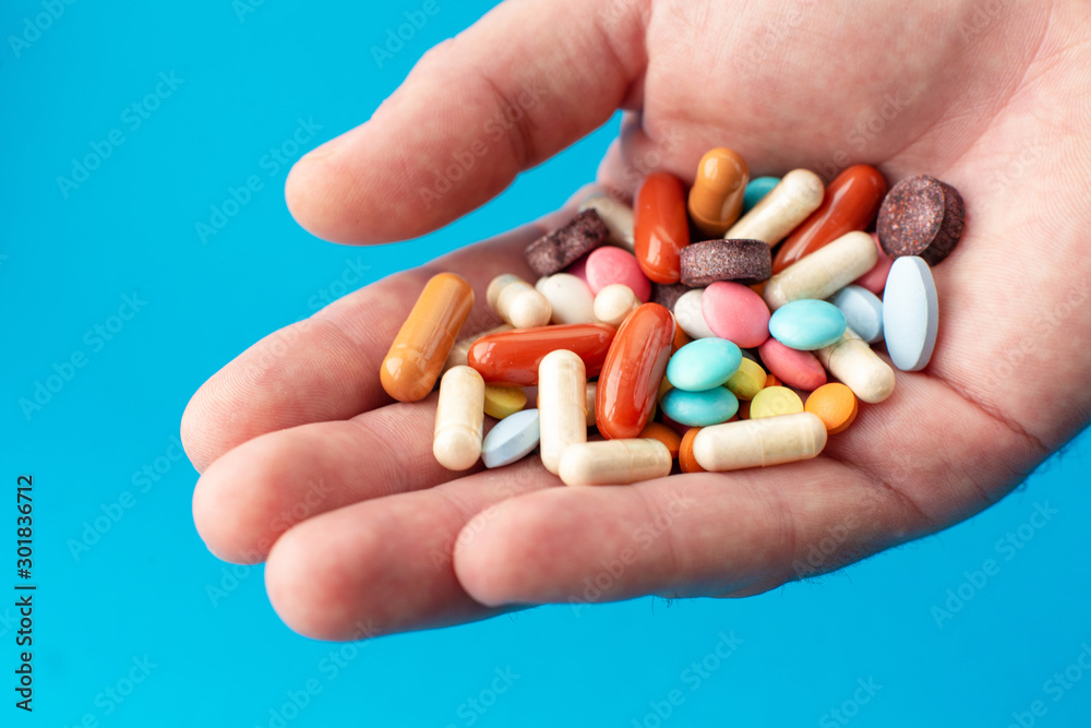 A handful of colored pills on the palm. Medical concept. Shopping at the pharmacy. A handful of colored pills on the palm. Medical concept. Shopping at the pharmacy.