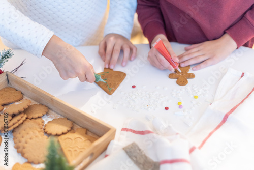 children decorate ginger Christmas cookies with sugar pencils