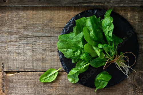 Leaves of fresh baby spinach on a rustic wooden table. Top view flat lay background with copy space.
