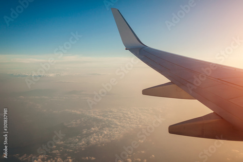 Plane window view of clouds and islands surrounded by sea and airplane wing. Traveling concept