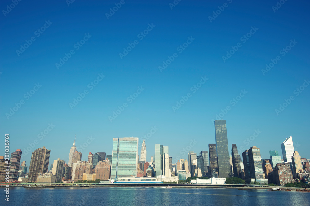 Sunny morning view of the New York City skyline with bright blue cloudless sky above East River