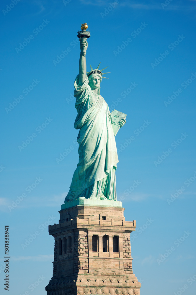 Fototapeta premium Full length view of the Statue of Liberty standing against bright blue sky on a clear sunny summer day in New York City, USA