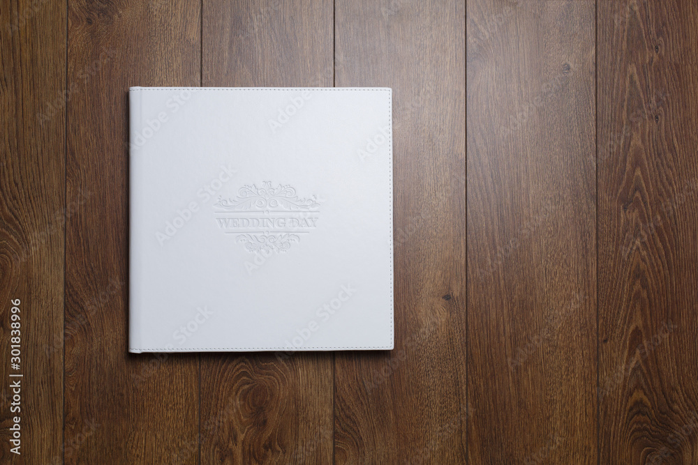 family photo book with white fabric cover. white wedding photo album on a wooden background with space for text. white photobook close up. photoalbum with a beautiful stylish cover family photo book with white fabric cover. white wedding photo album on a wooden background with space for text. white photobook close up. photoalbum with a beautiful stylish cover