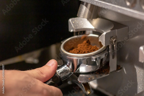 Male bartender on the workplace. Closeup image of male hands while making coffee using coffeegrinder and coffeemachine