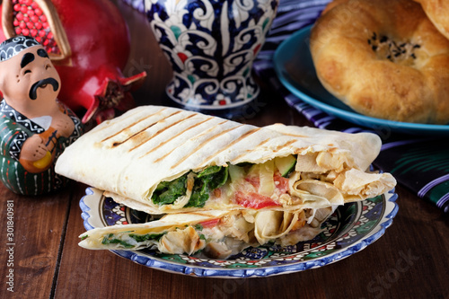 shawarma in thin pita bread with chicken and vegetables on a plate photo