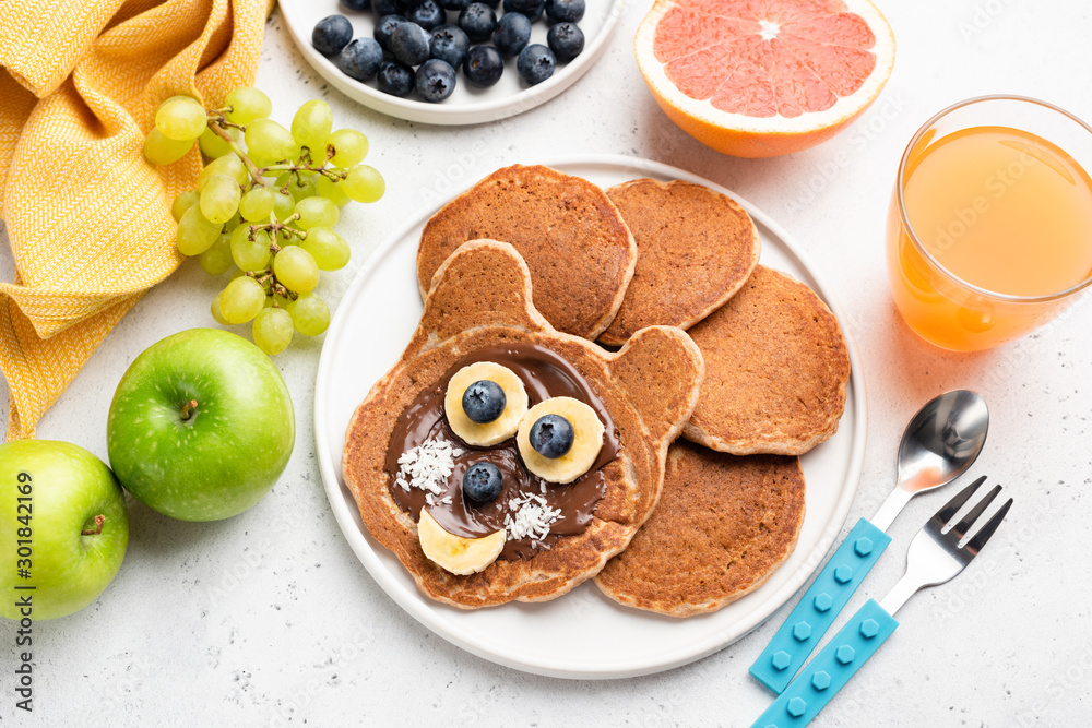 Naklejka Funny cat pancakes with chocolate spread and banana for kids on a plate. Baby food, pancake food art concept