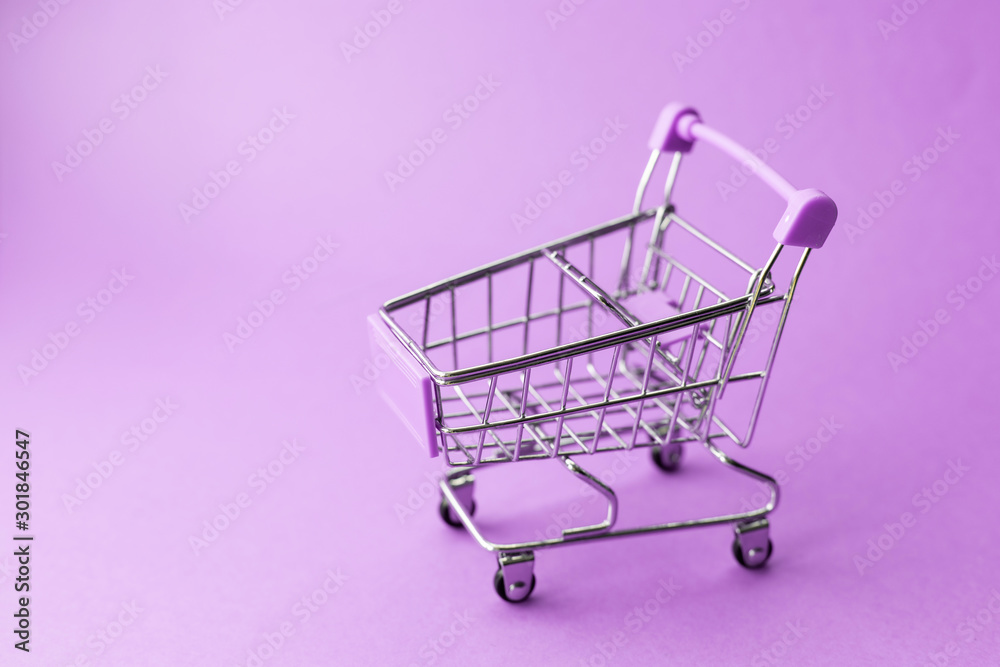 empty metal shopping trolley on purple background. Discount and shopping concept empty metal shopping trolley on purple background. Discount and shopping concept