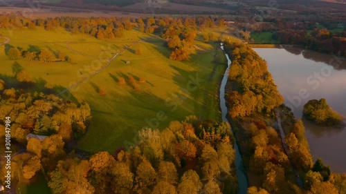 Aerial footage during late Fall Autumn of a river reflecting the sunset over rural England in the countryside, West Yorkshire, UK - Wakefield