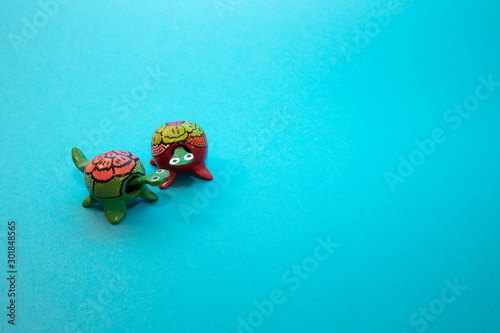 Two handmade turtles looking at each other on a blue surface