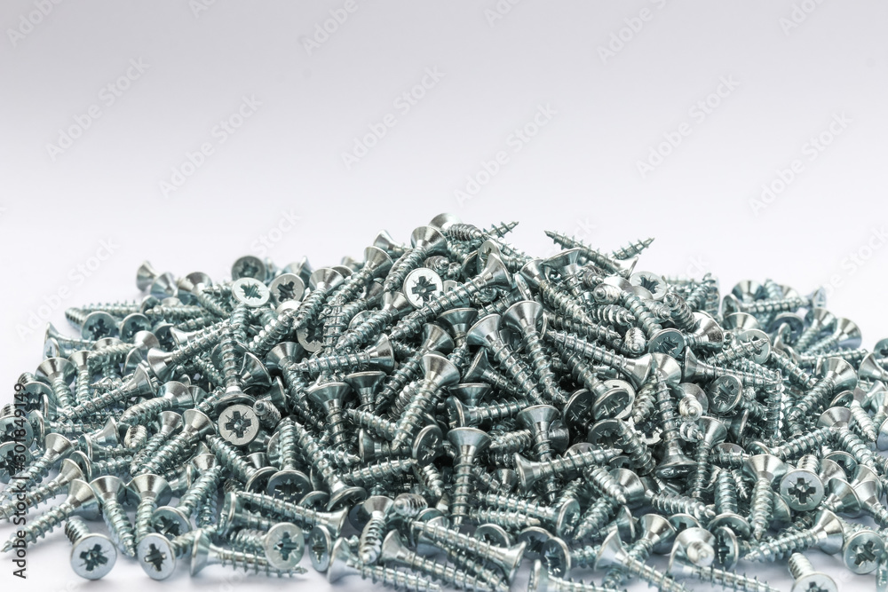 Small pile of Metal galvanized screws.  20 mm screws side view.  Fixing materials on a white background.  Isolated heap of wood screws. - obrazy, fototapety, plakaty 