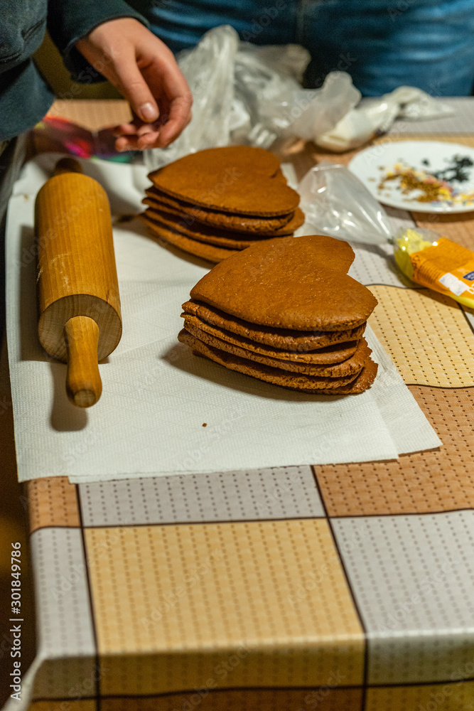 Heart shaped gingerbread cookies stacked on the table next to dough roll