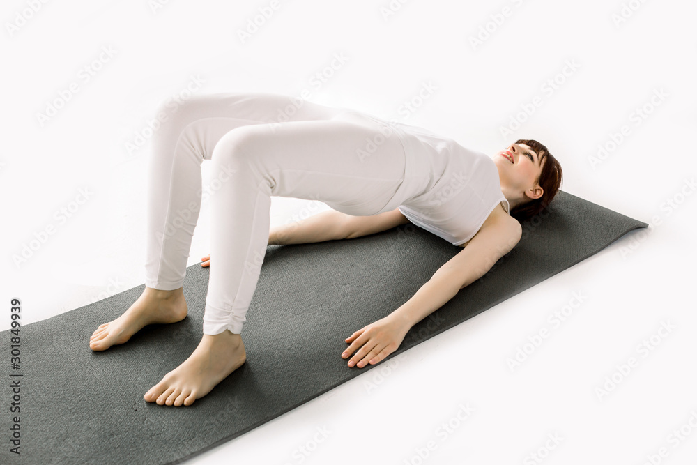 Side view portrait of beautiful young woman working out in fitness club or at home, doing yoga, pilates exercise. Vutt bridge, shoulder bridge pose. Full length Side view portrait of beautiful young woman working out in fitness club or at home, doing yoga, pilates exercise. Vutt bridge, shoulder bridge pose. Full length