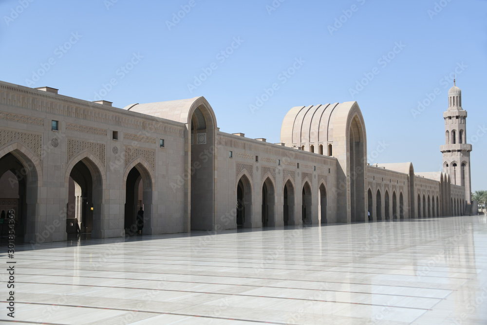 Im Äußeren Sahn ist das Gebäude mit den Waschräumen für Männer und Frauen im Bogengang dem Riwaq in der Großen Sultan-Qabus-Moschee in Makat, Oman zu sehen.