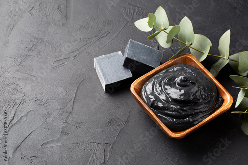 Spa and bath concept. Dead sea mud, coal black soap, eucalyptus on black background. Copy space.