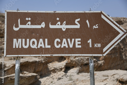 Ein Schild welches zu den Muqal Höhlen im berühmten Wadi Bani Khalid führt. Es  liegt im Distrikt Schamal asch Scharqiyya im Hadschar Gebirge  Die Oase  befindet sich im Sultanat Oman. photo