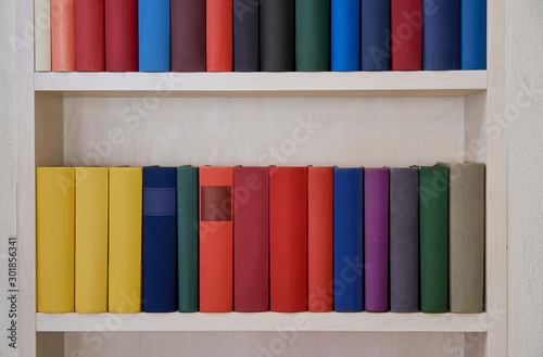 Part of bookcase with colorful covers in white wall