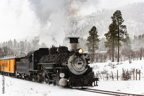 Vintage Steam Train kłębiący się dym w śniegu, gdy porusza się po górach.
