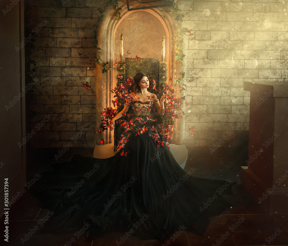 Fototapeta premium gotycka ciemna królowa siedzi w zamku na złotym tronie. czarna sukienka w motyle. Mur z cegły, duża gotycka sala, magiczne promienie słońca z okna. Modna jedwabna spódnica z długim trenem. Wspaniała kobieta fantasy